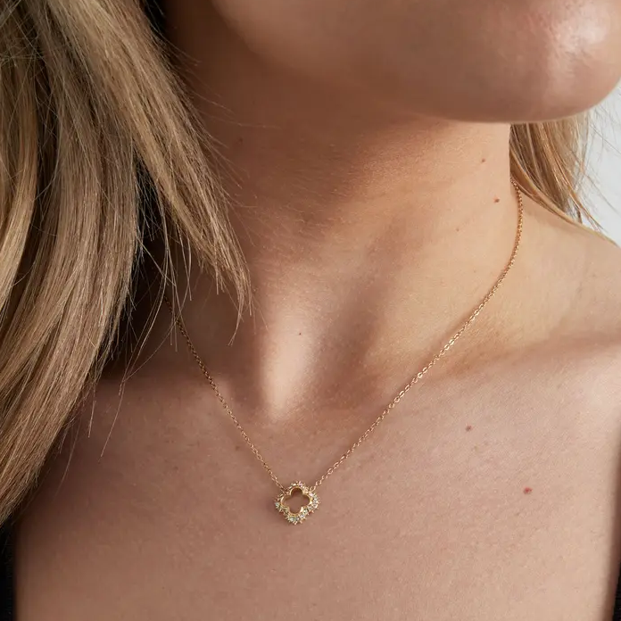 Frau trägt eine filigrane Halskette mit vierblättriger Blumenform in Gold von Ankerliebe