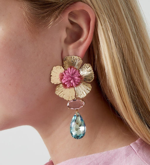 Tragebild: goldene Fleuria Blue Ohrhänger mit pinker Mitte & blauem Tropfenanhänger – floraler Statement-Schmuck am Ohr