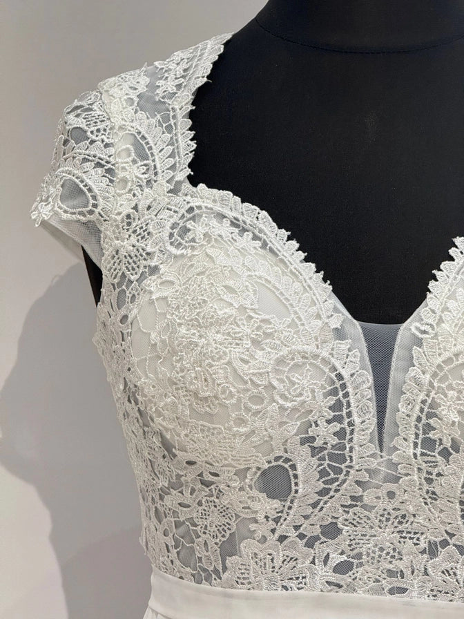 Brautkleid in Ivory mit transparentem Spitzentop, Tülleinsatz und fließendem Chiffonrock. Fein gearbeiteter Rücken mit Zipper.