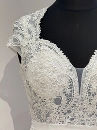 Brautkleid in Ivory mit transparentem Spitzentop, Tülleinsatz und fließendem Chiffonrock. Fein gearbeiteter Rücken mit Zipper.