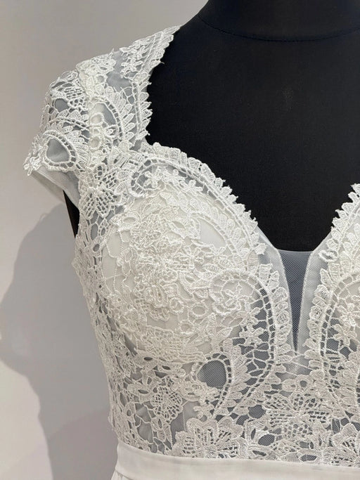 Brautkleid in Ivory mit transparentem Spitzentop, Tülleinsatz und fließendem Chiffonrock. Fein gearbeiteter Rücken mit Zipper.