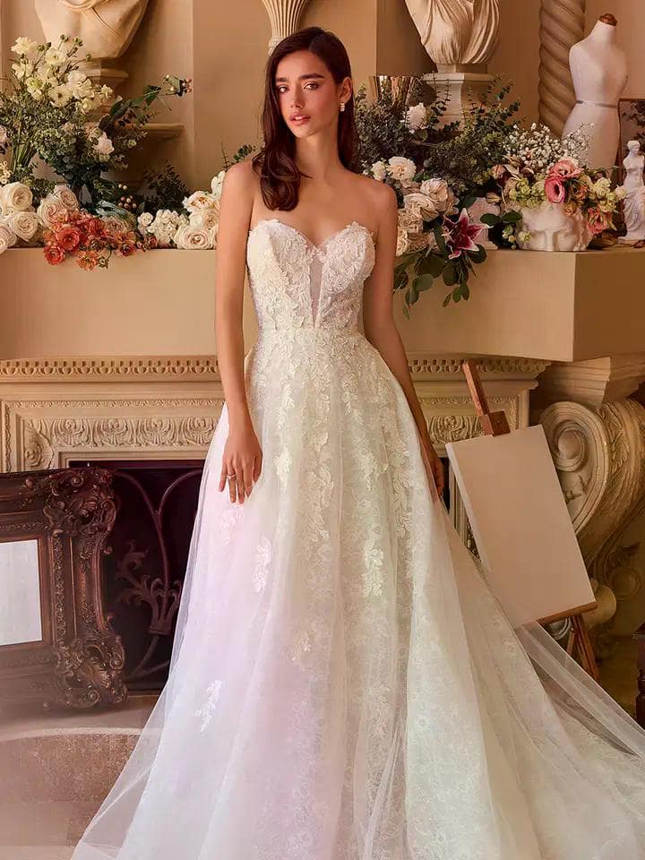 Braut trägt ein trägerloses A-Linien-Brautkleid mit floraler Spitze und Herzausschnitt, im eleganten, floralen Ambiente.