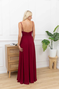 Model trägt ein burgunderrotes Abendkleid mit Herzausschnitt, Drapierung, hohem Schlitz und zarten Trägern – eleganter Look für besondere Anlässe.