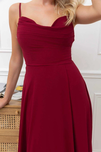 Model trägt ein burgunderrotes Abendkleid mit Herzausschnitt, Drapierung, hohem Schlitz und zarten Trägern – eleganter Look für besondere Anlässe.