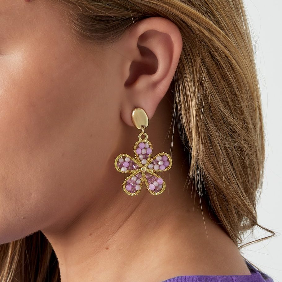 Statement Ohrhänger in Lila mit Blumenform getragen am Ohr – goldene Fassung mit Perlen von Ankerliebe