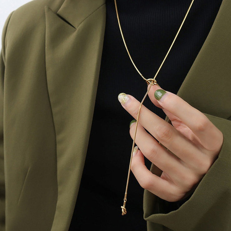 Detailaufnahme der Enya Halskette mit Knoten – Hand hält den Verschluss in Roségold