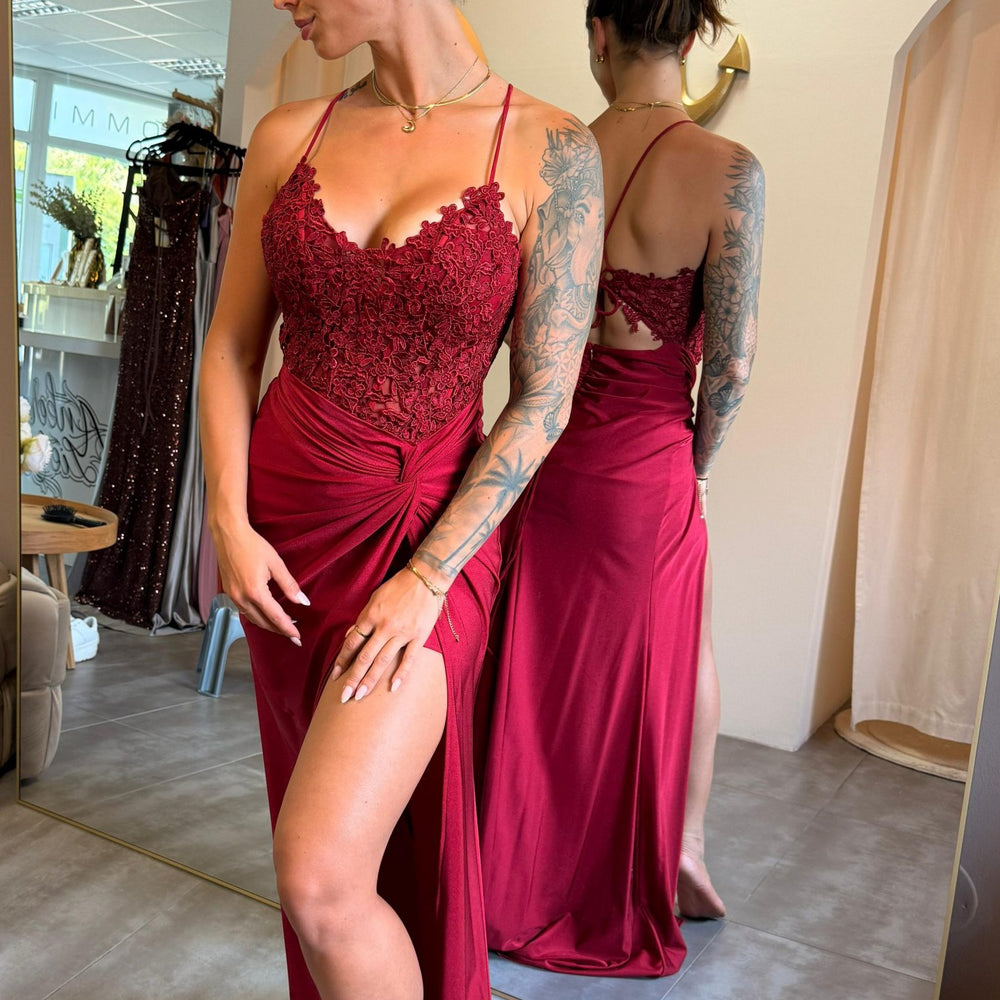 Model trägt das bordeauxrote Kleid „Ravena“ mit Spitzencorsage, Beinschlitz und Rückenschnürung – eleganter Look für große Events.