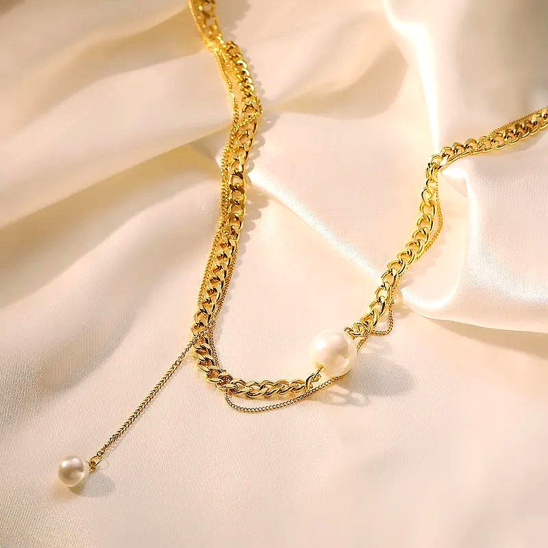 Goldene Edelstahlkette mit Perlenanhänger auf Satin-Hintergrund