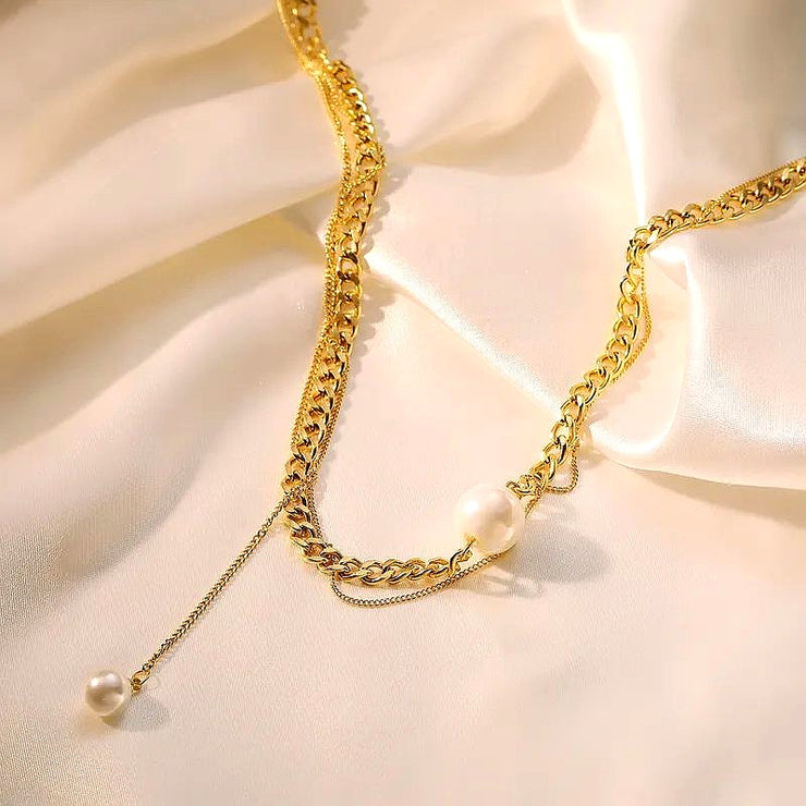 Goldene Edelstahlkette mit Perlenanhänger auf Satin-Hintergrund