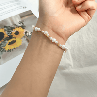 „Perlenarmband mit goldfarbener Kette elegant am weiblichen Handgelenk getragen“