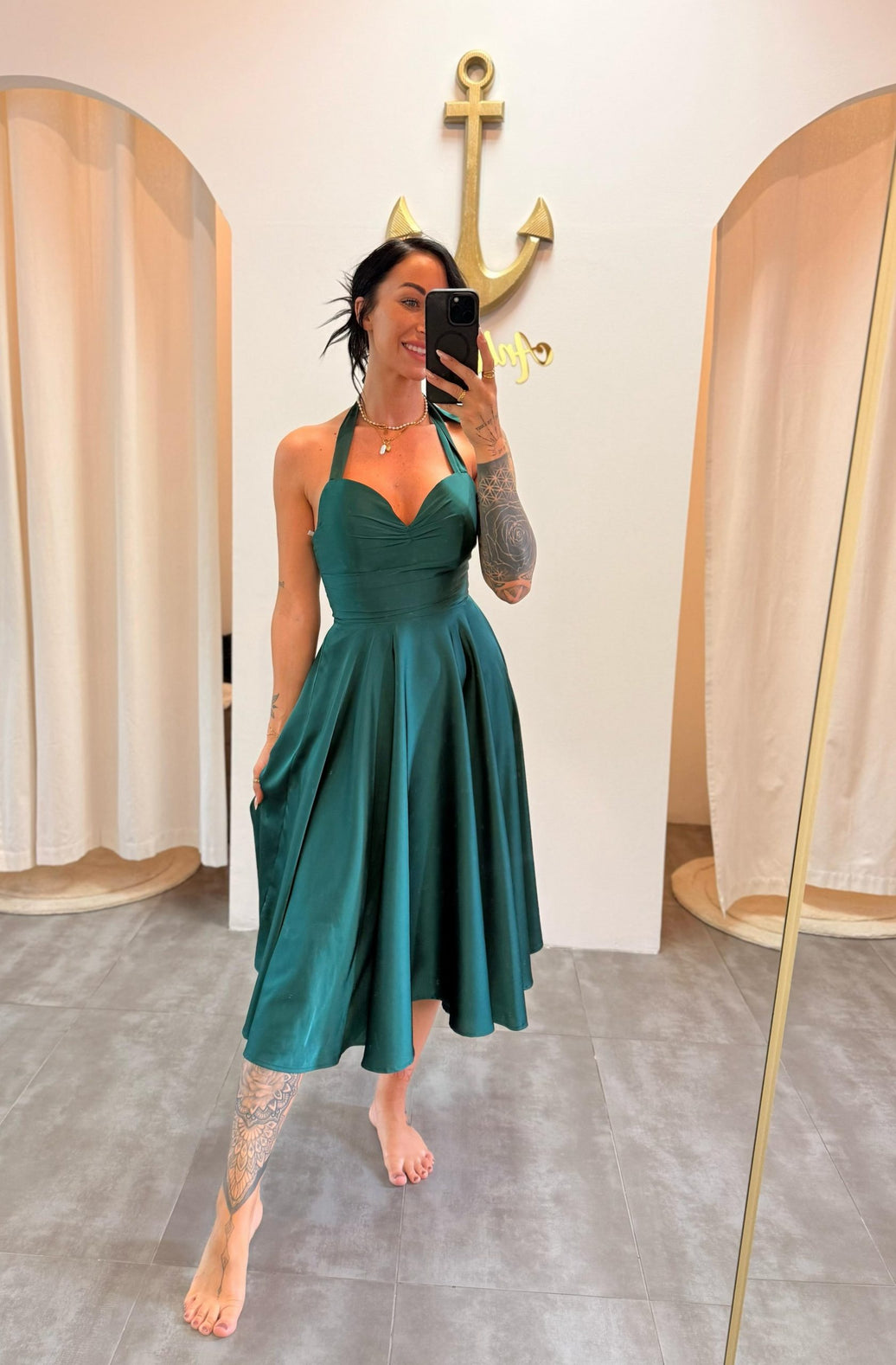 Frau trägt ein smaragdgrünes Satin-Midikleid mit Neckholder, schwingendem Rock und Taschen – fotografiert im Ankerliebe-Store.