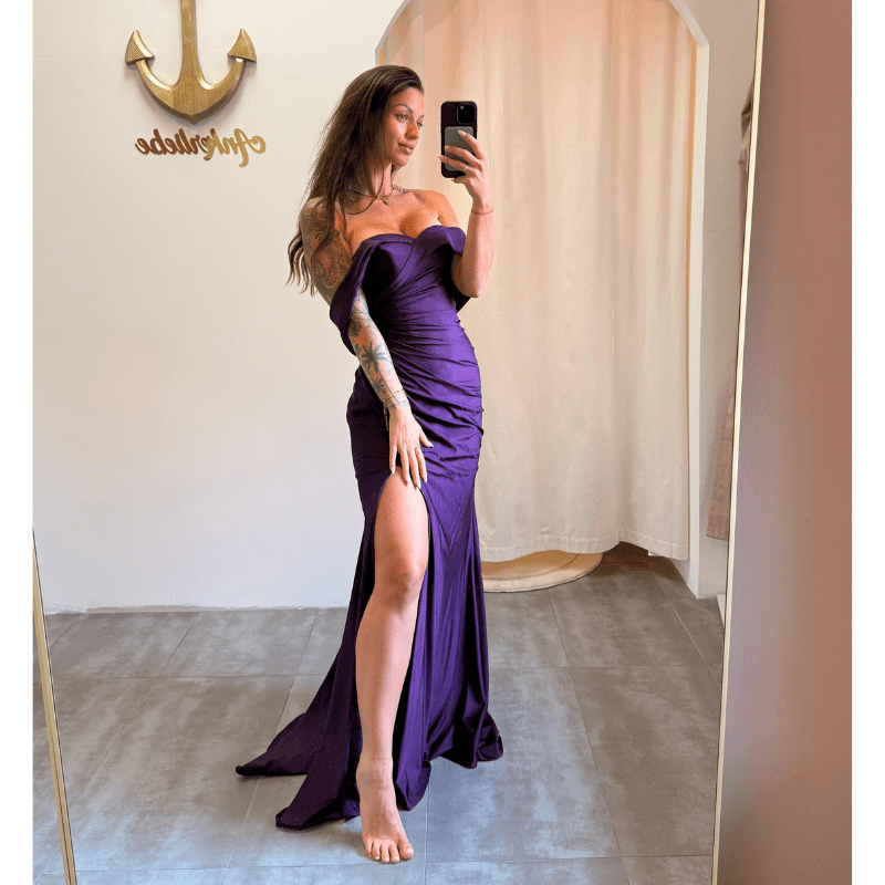 Model in einem dunkelvioletten Off-Shoulder Kleid mit Beinschlitz – Vorderansicht.